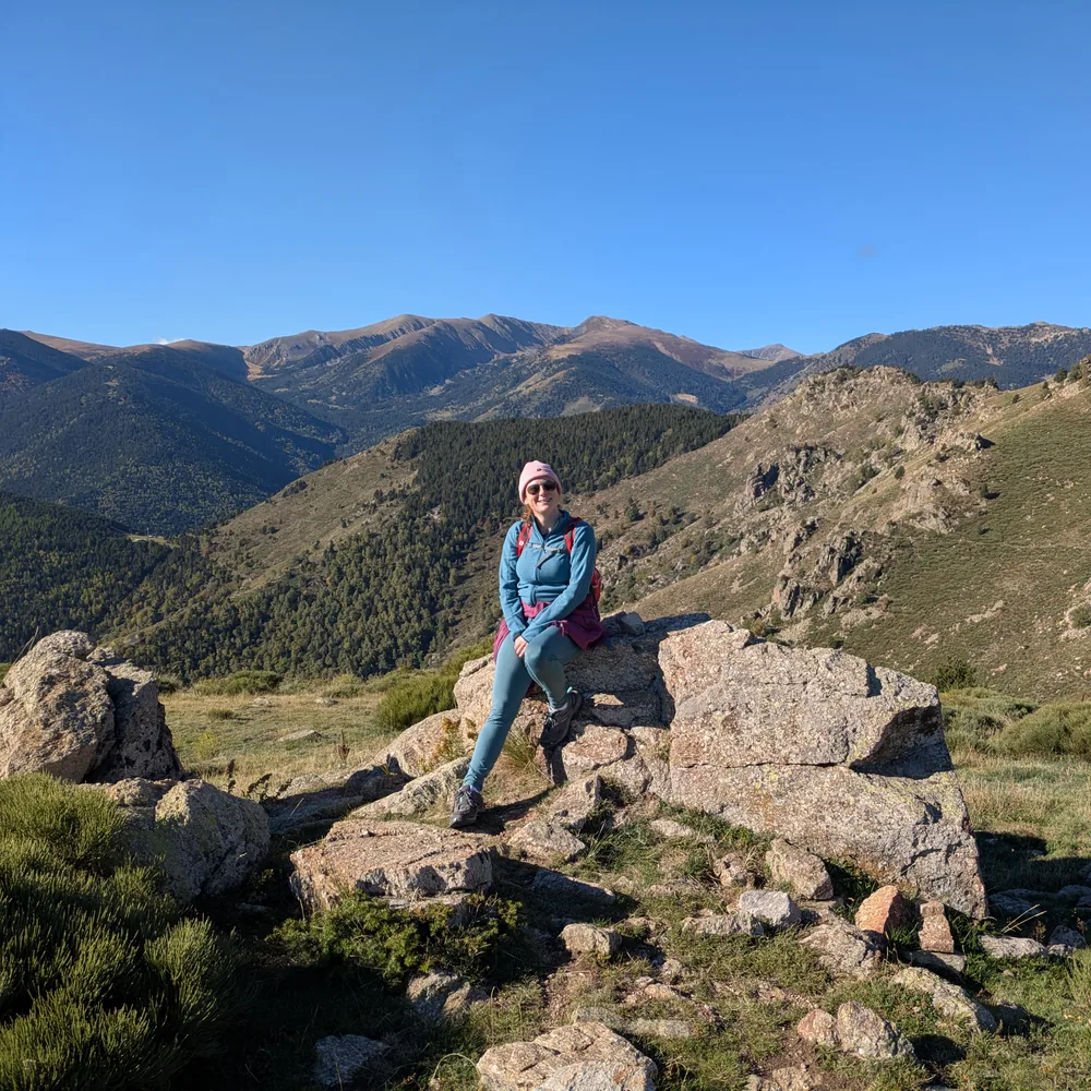 Elodie en randonnée en montagne, assise sur un rocher au soleil