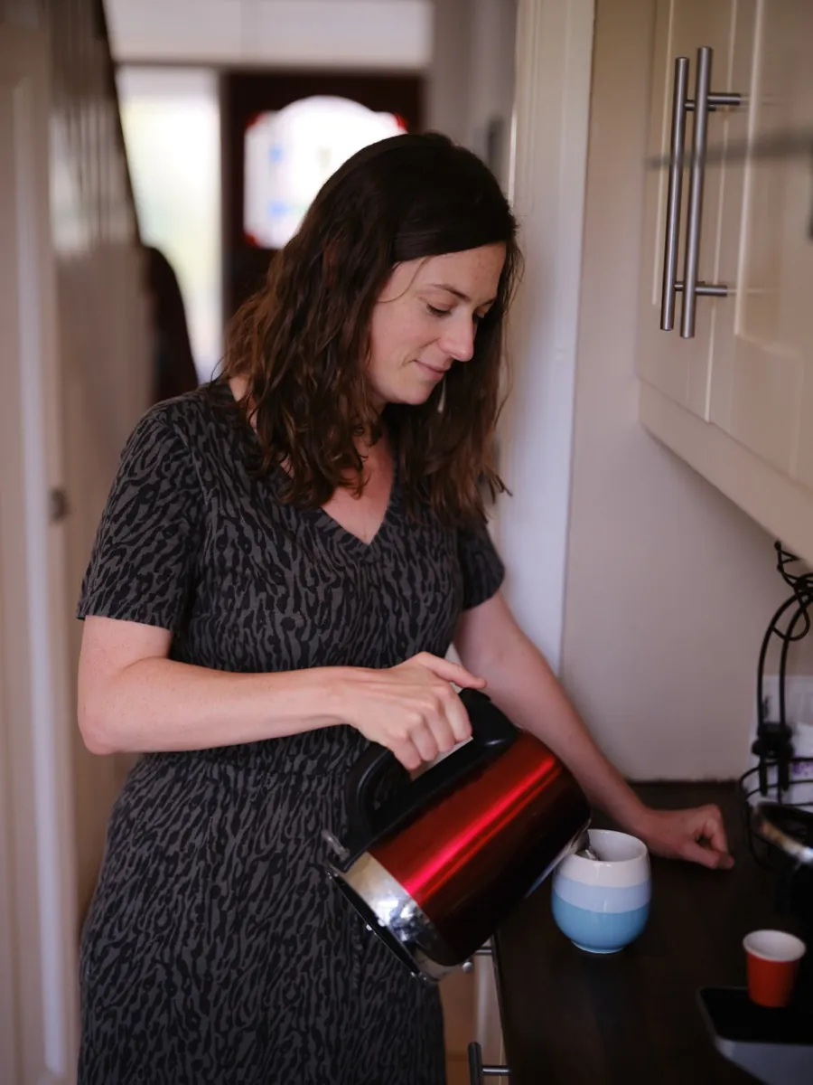 Elodie pouring hot water for a cup of tea in a family kitchen